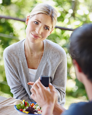 Buy stock photo Shot of a beautiful young woman looking uncertain as her boyfriend is proposing