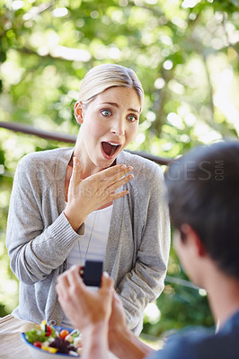 Buy stock photo Shot of a beautiful young woman looking surprised as her boyfriend is proposing