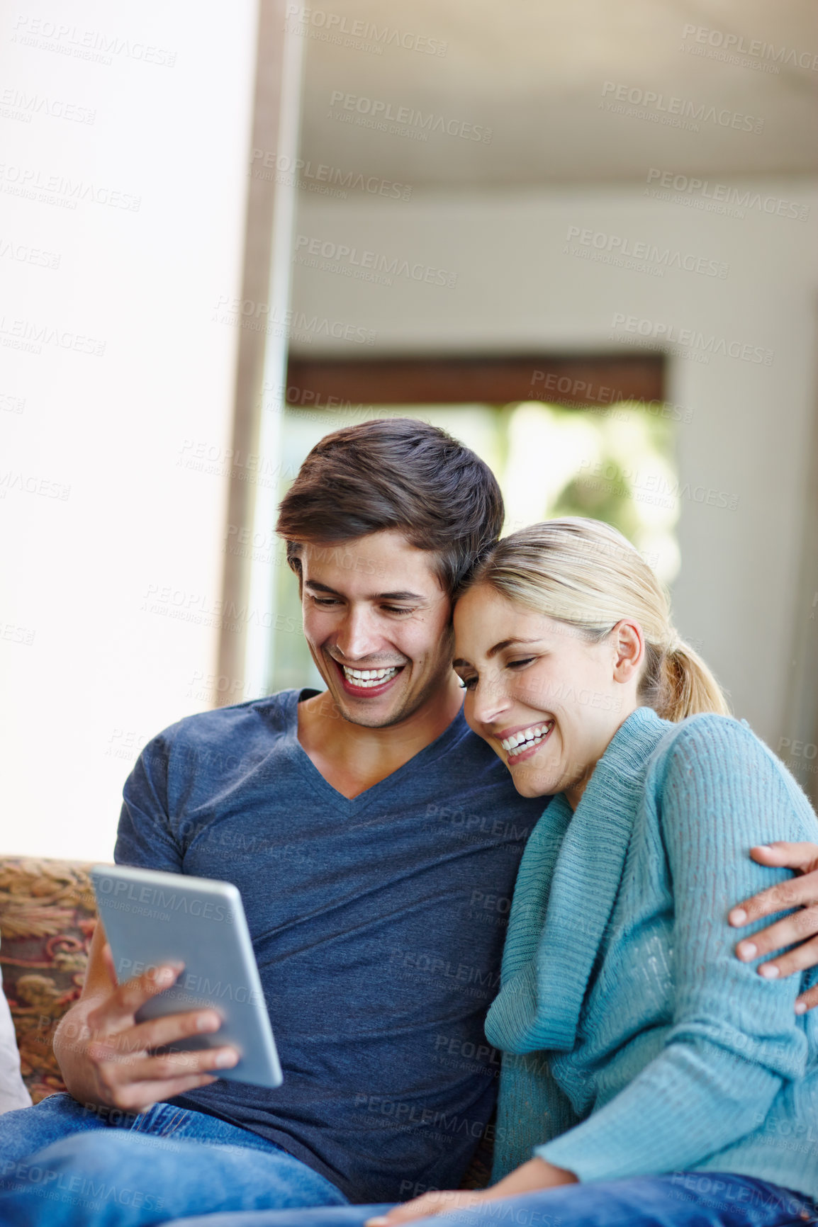 Buy stock photo Shot of a happy young couple using a digital tablet together on the sofa at home