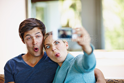 Buy stock photo Shot of a playful young couple taking a selfie together on a mobile phone
