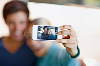 Buy stock photo Shot of a happy young couple taking a selfie together on a mobile phone