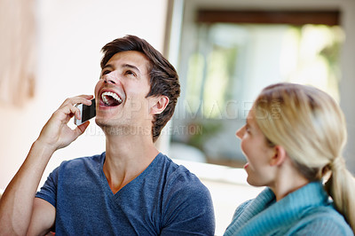 Buy stock photo Shot of an excited young couple receiving wonderful news from a caller on their mobile phone