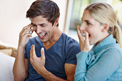 Buy stock photo Shot of an excited young couple receiving wonderful news from a caller on their mobile phone