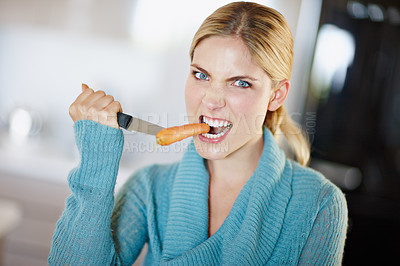 Buy stock photo Portrait of a beautiful young woman aggressively taking a bite out of a carrot