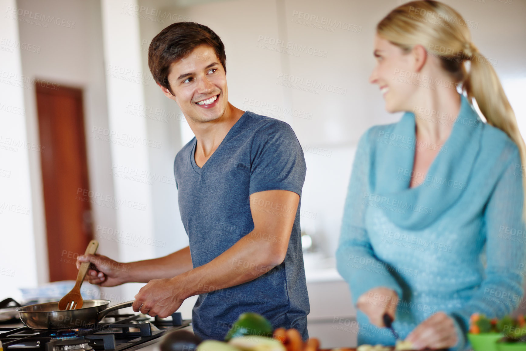 Buy stock photo Shot of a happy young couple cooking a meal together at home