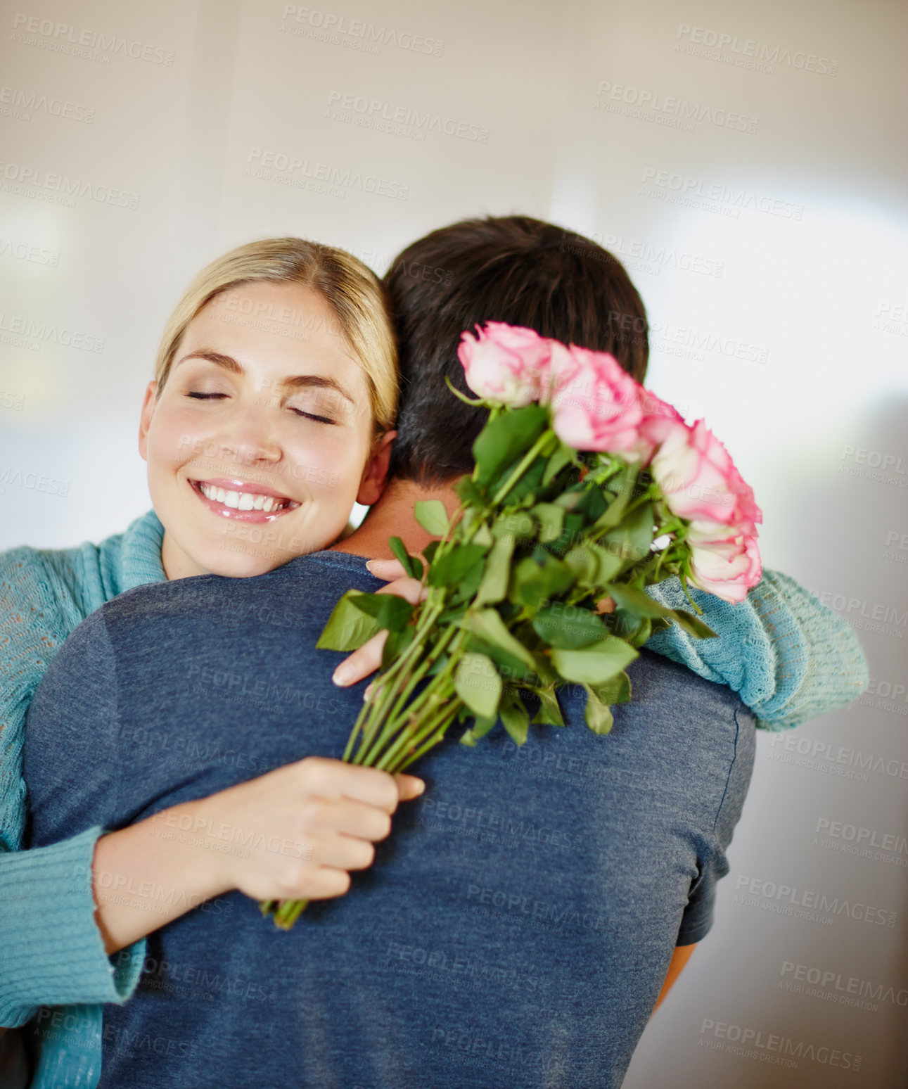 Buy stock photo Shot of an affectionate young man giving his beautiful young wife a bouquet of pink roses 
