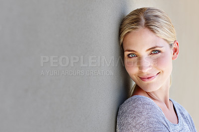 Buy stock photo Portrait of a happy young woman leaning against a gray wall