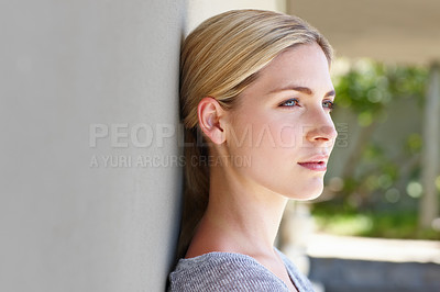 Buy stock photo Shot of a beautiful young woman leaning against a wall while deep in thought