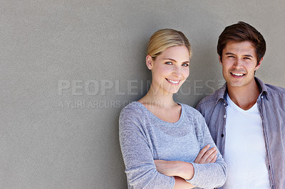 Buy stock photo Portrait of a confident young couple standing against a gray background