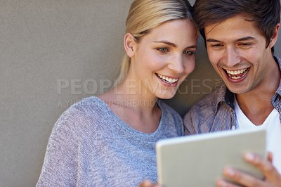 Buy stock photo Shot of a happy young couple using a digital tablet together against a gray background