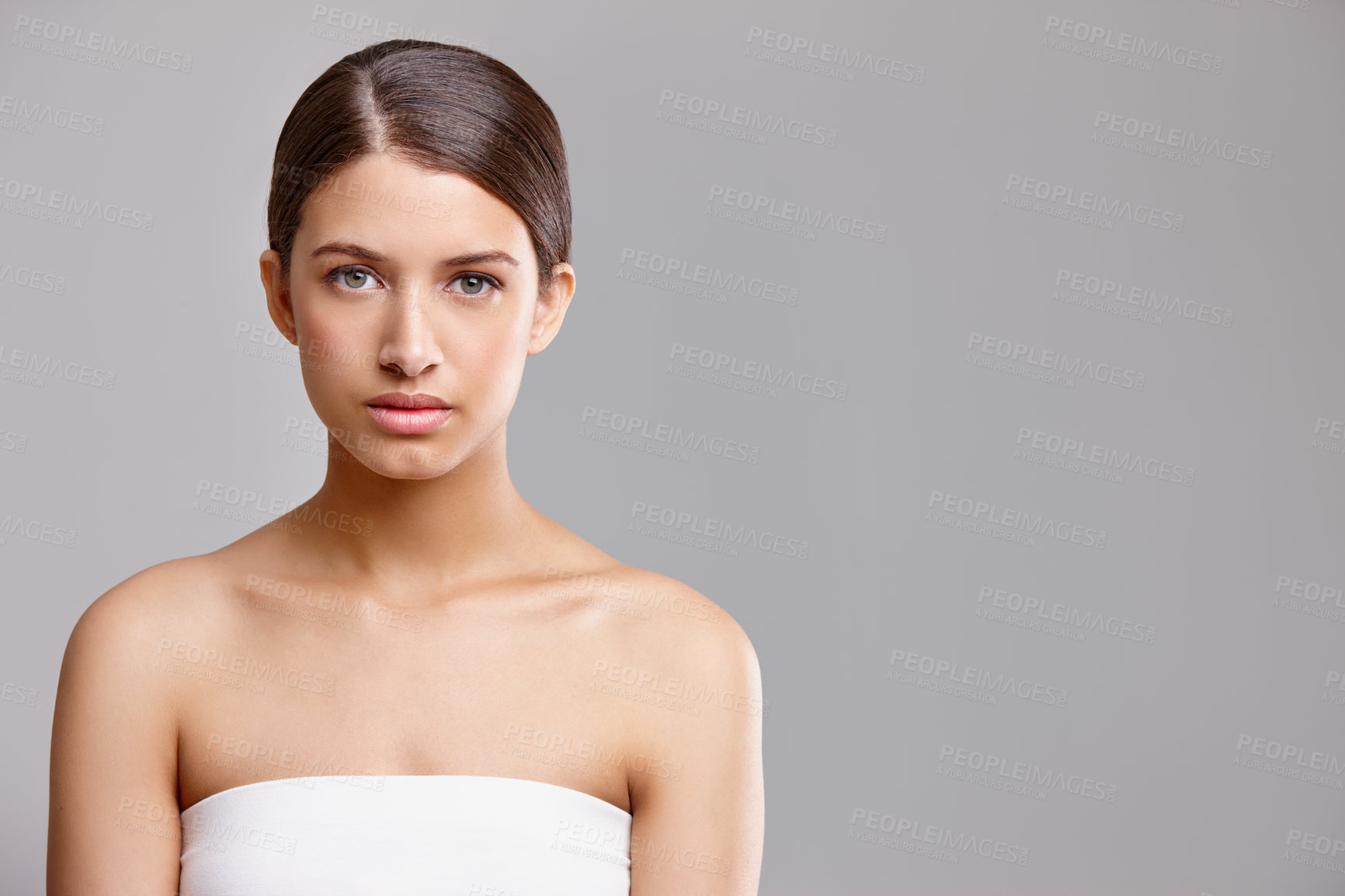 Buy stock photo Studio portrait of a beautiful young woman standing against a gray background