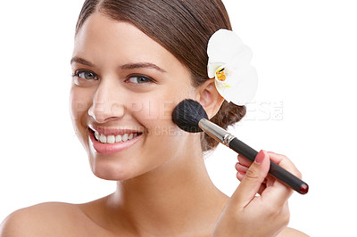 Buy stock photo Portrait of a beautiful young woman with an orchid in her hair applying blush to her cheeks