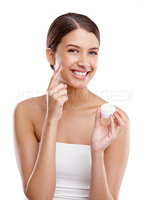 Buy stock photo Studio portrait of a beautiful young woman applying moisturizer to her skin