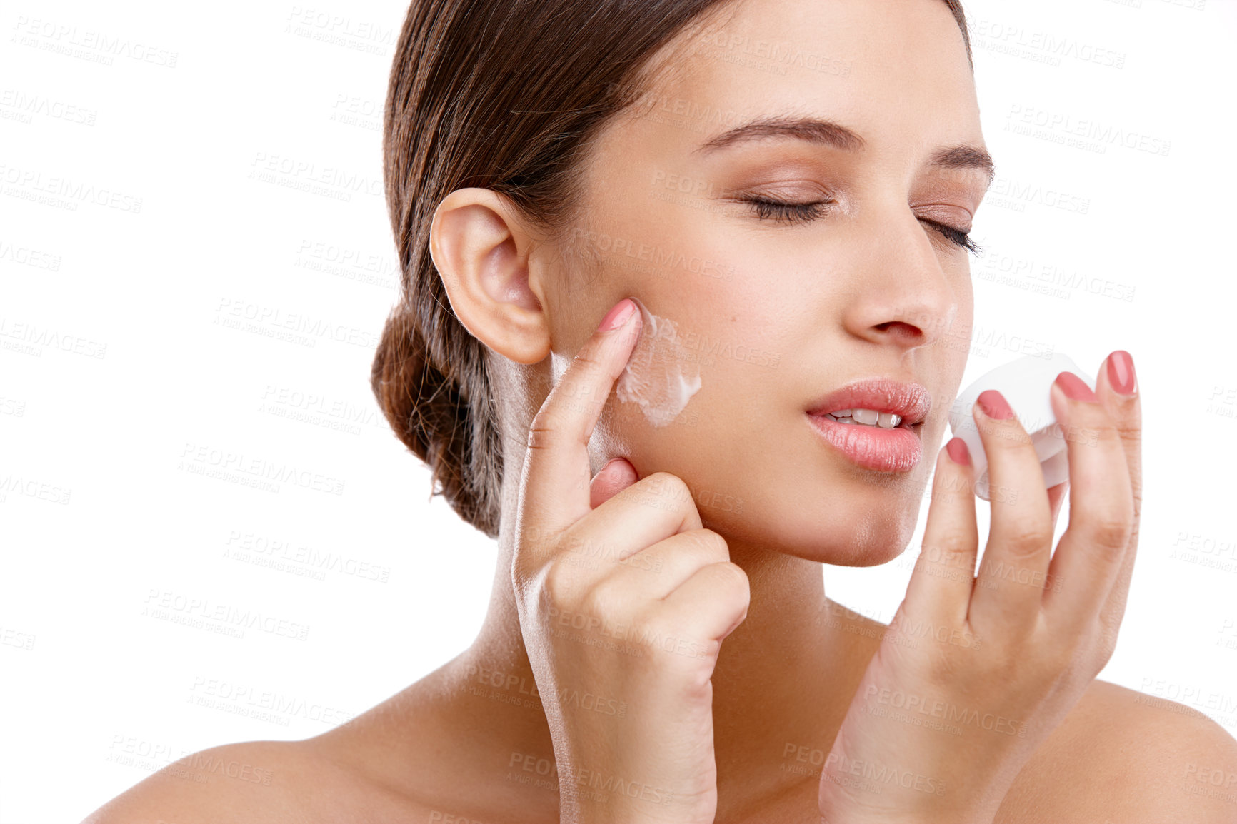 Buy stock photo Studio shot of a beautiful young woman applying moisturizer to her skin