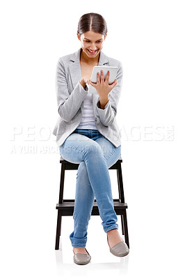 Buy stock photo Studio shot of a beautiful young woman sitting on a stool and using a digital tablet against a white background