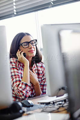 Buy stock photo A young designer looking relieved while talking on her phone