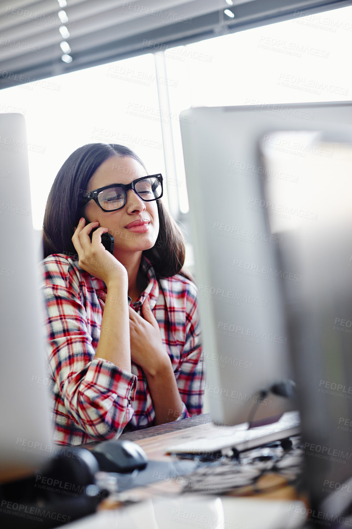 Buy stock photo A young designer looking relieved while talking on her phone