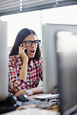 Buy stock photo Shot of a young designer looking displeased while talking on her phone