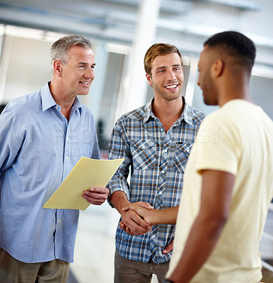 Buy stock photo Shot of a young man shaking hands with his coworker in the office