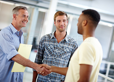 Buy stock photo Shot of a young man shaking hands with his coworker in the office