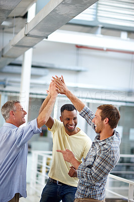 Buy stock photo Shot of three coworkers giving each other a high five at the office
