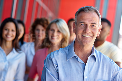 Buy stock photo Shot of a confident man standing in front of his team in a casual office environment