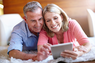 Buy stock photo Shot of a loving husband and wife using a digital tablet together at home