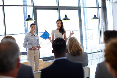 Buy stock photo Shot of two young businesswomen giving a presentation to their coworkers