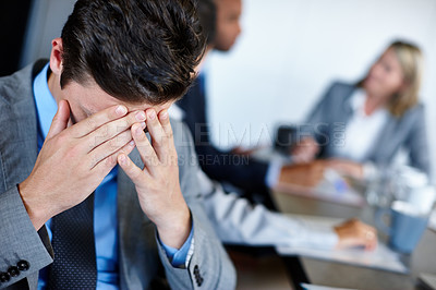 Buy stock photo Shot of a young businessman suffering from stress during a meeting with his colleagues