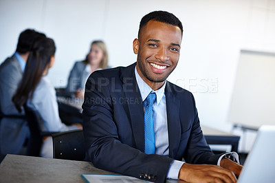 Buy stock photo Shot of a handsome young businessman working on a laptop in the office