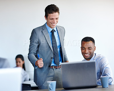 Buy stock photo Shot of two young coworkers working together on a laptop in the office