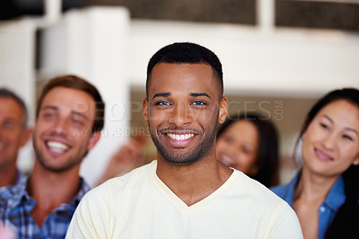 Buy stock photo Portrait of a young businessman with his colleagues sitting behind him