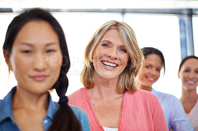 Buy stock photo Portrait of a mature woman standing with her business colleagues at the office