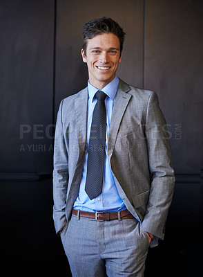 Buy stock photo Portrait of a smiling young businessman in a suit standing with his hands in his pockets