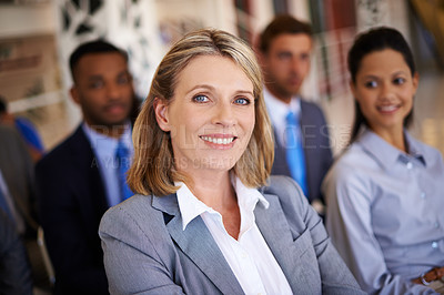 Buy stock photo Portrait of an attractive mature businesswoman with her colleagues sitting behind her