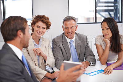 Buy stock photo Shot of a businessman showing his colleagues something on a tablet in a meeting