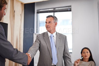 Buy stock photo Cropped shot of two businessmen shaking hands with a colleague in the background