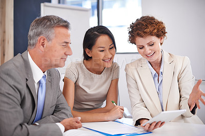 Buy stock photo Shot of a businesswoman showing her colleagues something on a tablet in a meeting