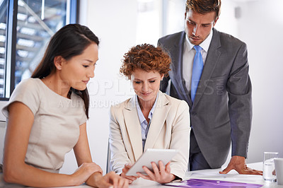 Buy stock photo Shot of a businesswoman showing her colleagues something on a tablet in a meeting