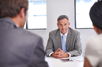 Buy stock photo Shot of a mature businessman in a meeting with his employees