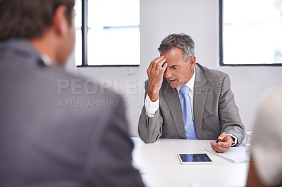 Buy stock photo Shot of a mature businessman looking displeased in a meeting with his employees
