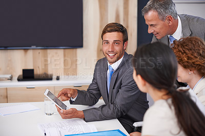 Buy stock photo Shot of a young businessman using a tablet in a meeting with his colleagues