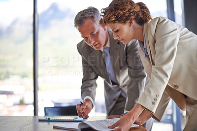 Buy stock photo Shot of a mature businessman signing the documents his employee brought him