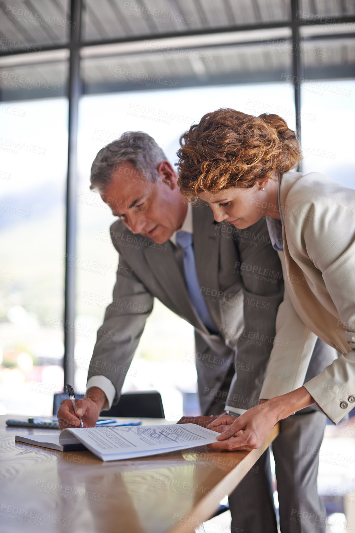 Buy stock photo Shot of a mature businessman signing the documents his employee brought him