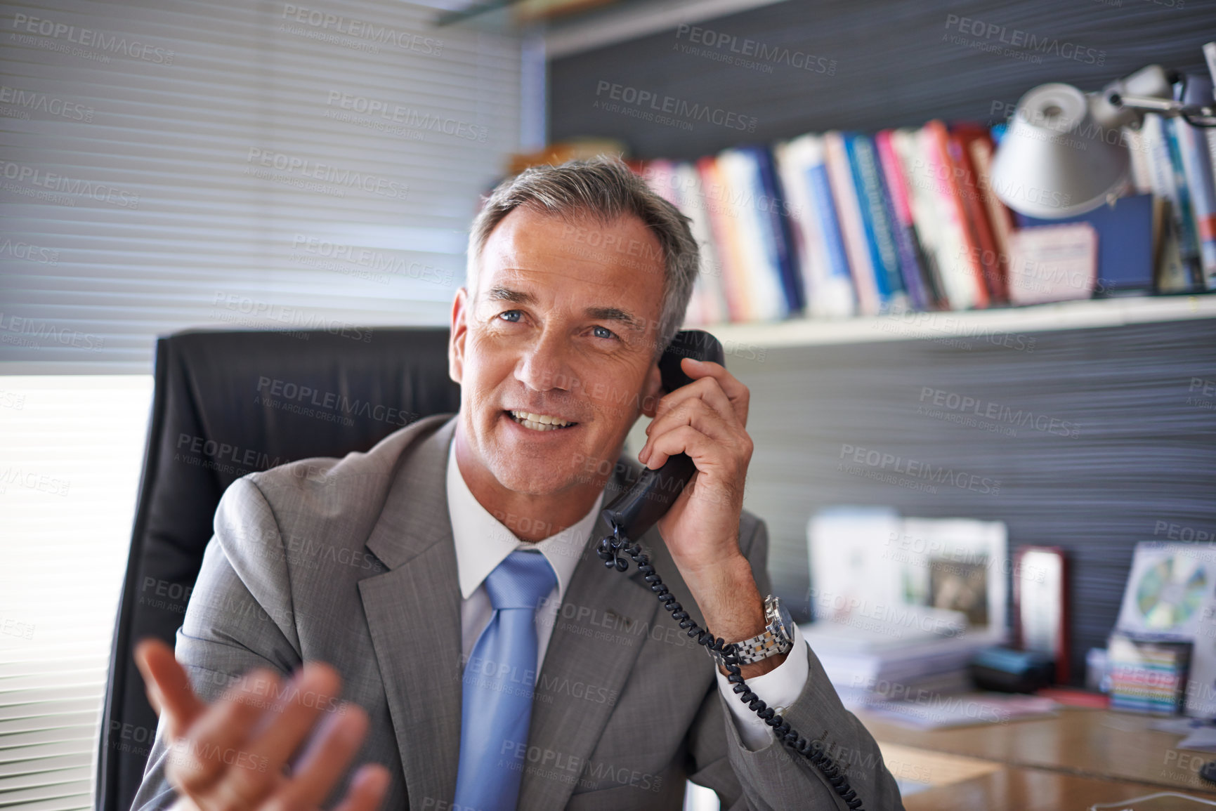 Buy stock photo Shot of a mature businessman looking pleased while talking on the phone in his office