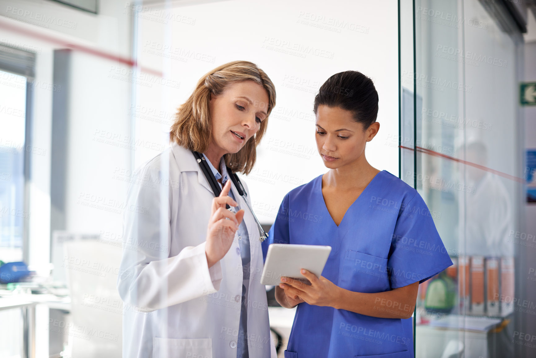 Buy stock photo Shot of a female doctor giving a nurse instructions at a hospital