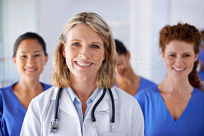 Buy stock photo Portrait of a mature female doctor with a group of nurses standing behind her