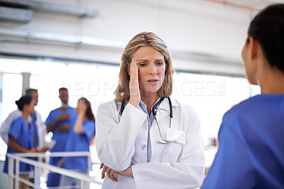 Buy stock photo Shot of an overworked doctor talking to a nurse in a hospital corridor