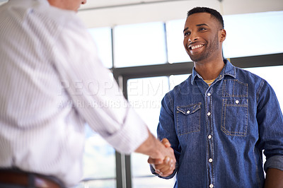 Buy stock photo Shot of two colleagues shaking hands in an informal office setting