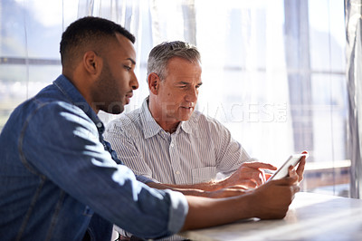 Buy stock photo Shot of two colleagues working together in an informal office setting